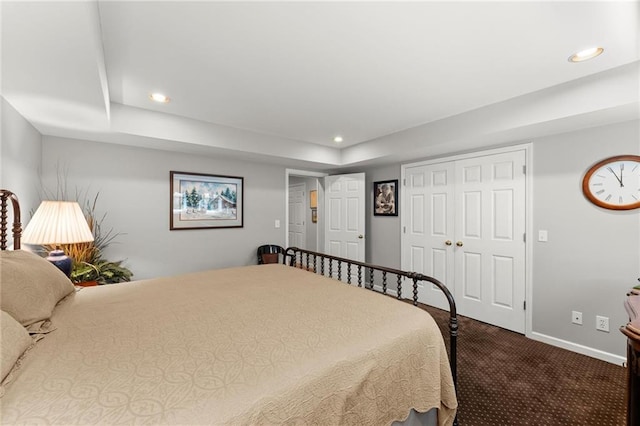 bedroom featuring a closet, baseboards, a tray ceiling, recessed lighting, and carpet flooring
