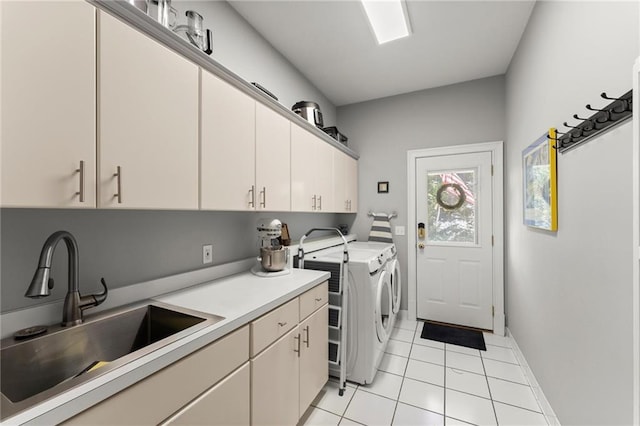 laundry room featuring light tile patterned floors, baseboards, a sink, cabinet space, and washing machine and dryer
