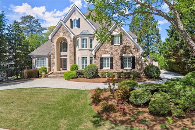 traditional home featuring stucco siding, stone siding, and a front yard