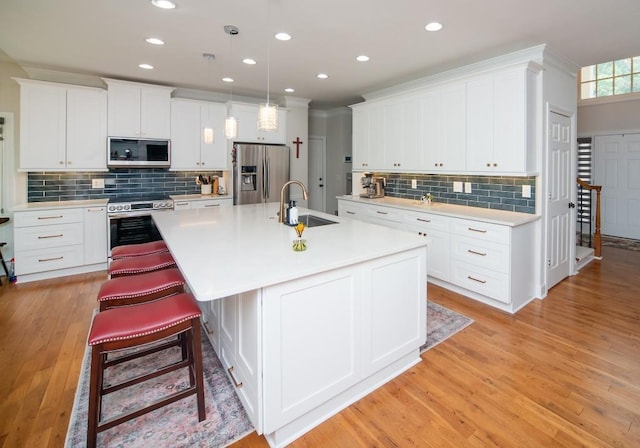 2521 Wood Creek Ct, Dacula, GA 30019 - kitchen featuring stainless steel appliances, tasteful backsplash, light countertops, an island with sink, and white cabinetry