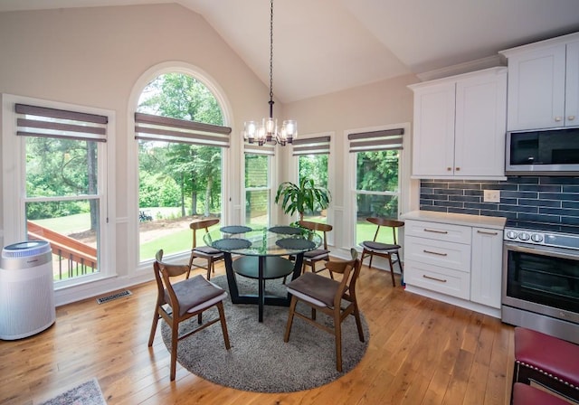 2521 Wood Creek Ct, Dacula, GA 30019 - dining space with light wood-type flooring, a chandelier, and high vaulted ceiling