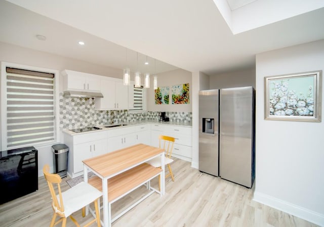 2521 Wood Creek Ct, Dacula, GA 30019 - kitchen with stainless steel fridge with ice dispenser, under cabinet range hood, light countertops, tasteful backsplash, and light wood finished floors