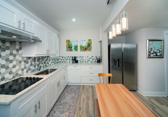 2521 Wood Creek Ct, Dacula, GA 30019 - kitchen with stainless steel fridge with ice dispenser, black electric cooktop, under cabinet range hood, light wood-style floors, and tasteful backsplash