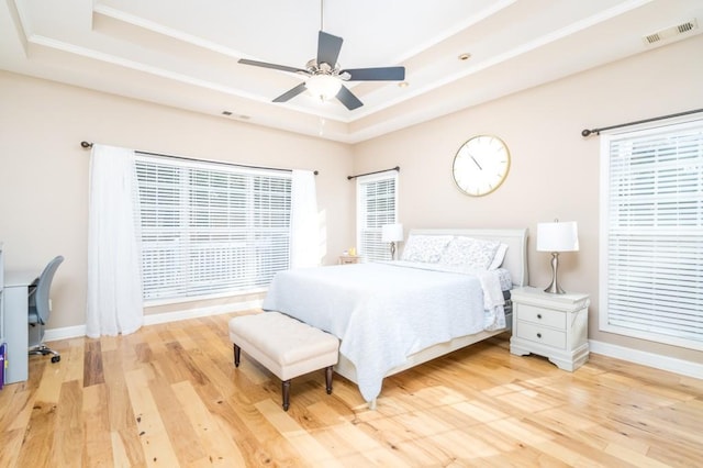 bedroom featuring ceiling fan, hardwood / wood-style floors, and a tray ceiling