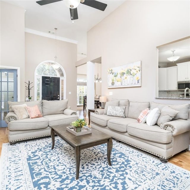 living room featuring high vaulted ceiling, ceiling fan, and light wood-type flooring