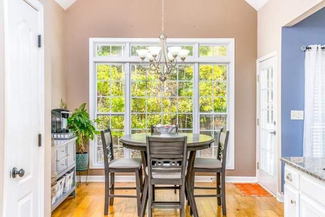 dining space featuring light hardwood / wood-style flooring, a chandelier, and vaulted ceiling