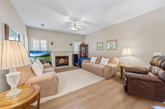 3652 Morning Creek Ct, Suwanee, GA 30024 - living room featuring a ceiling fan, light wood finished floors, and a lit fireplace