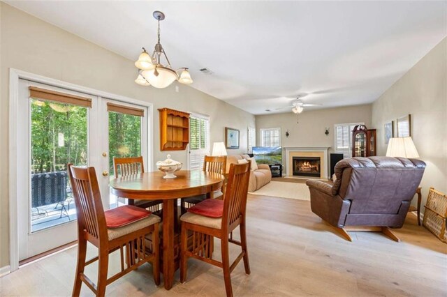 3652 Morning Creek Ct, Suwanee, GA 30024 - dining space featuring a lit fireplace, ceiling fan, a chandelier, and light wood-style floors