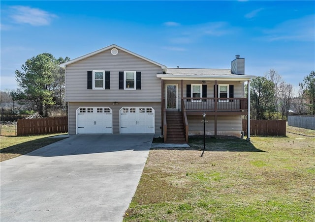 split level home with covered porch, concrete driveway, stairway, an attached garage, and fence