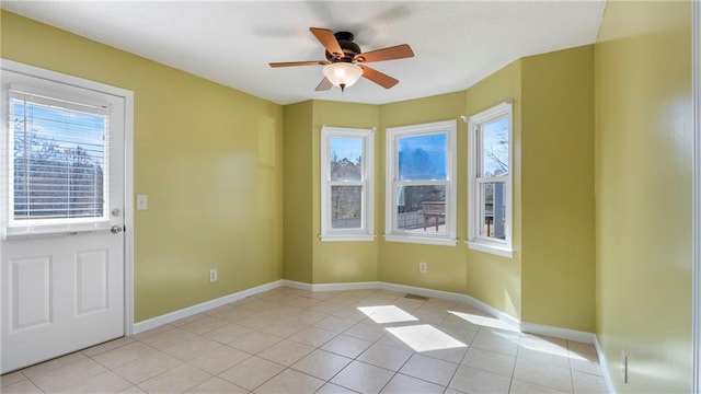 unfurnished room with a ceiling fan, light tile patterned flooring, and baseboards