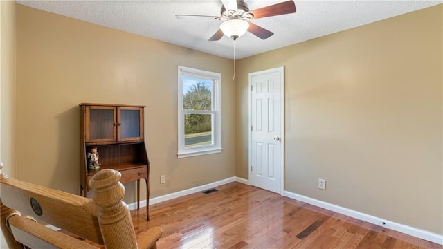 living area featuring baseboards, ceiling fan, and light wood-style floors