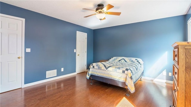 bedroom featuring visible vents, ceiling fan, baseboards, and wood finished floors