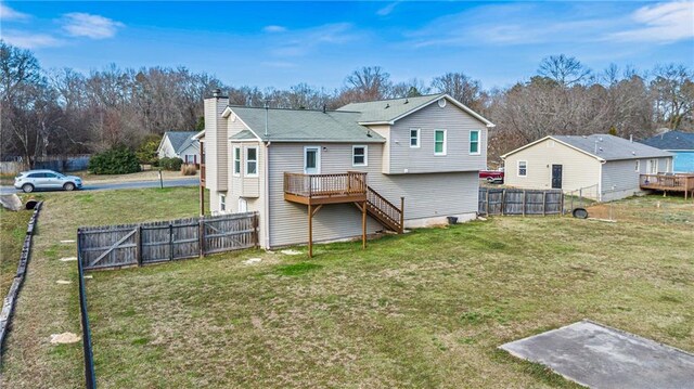 rear view of property with a deck, a yard, a chimney, and a fenced backyard