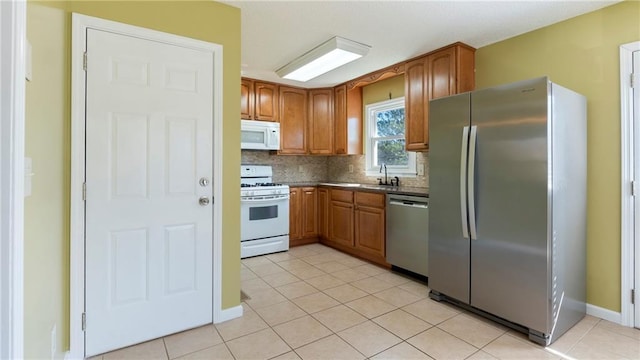 kitchen with decorative backsplash, appliances with stainless steel finishes, brown cabinetry, light tile patterned flooring, and a sink