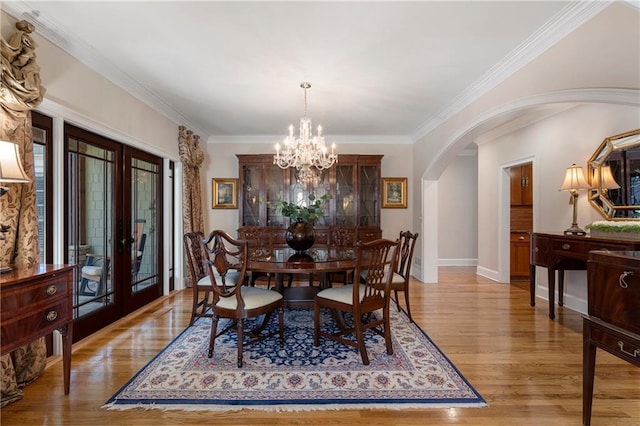 2160 Bradley Trl, Cumming, GA 30041 - dining space with french doors, arched walkways, light wood finished floors, crown molding, and a chandelier