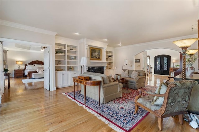 2160 Bradley Trl, Cumming, GA 30041 - living room with arched walkways, light wood-style flooring, crown molding, a fireplace, and built in features