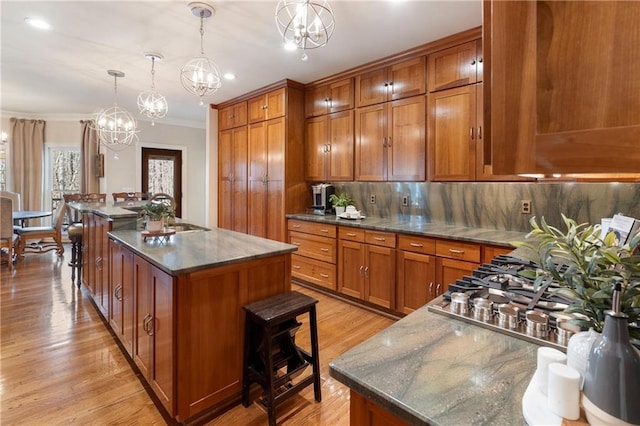 2160 Bradley Trl, Cumming, GA 30041 - kitchen featuring brown cabinets, a chandelier, a sink, a kitchen island with sink, and crown molding