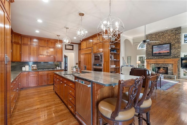 2160 Bradley Trl, Cumming, GA 30041 - kitchen featuring stainless steel appliances, a sink, light wood-type flooring, a fireplace, and recessed lighting