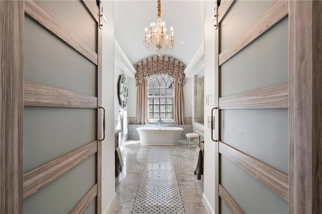2160 Bradley Trl, Cumming, GA 30041 - bathroom featuring lofted ceiling, a chandelier, a soaking tub, and a wainscoted wall