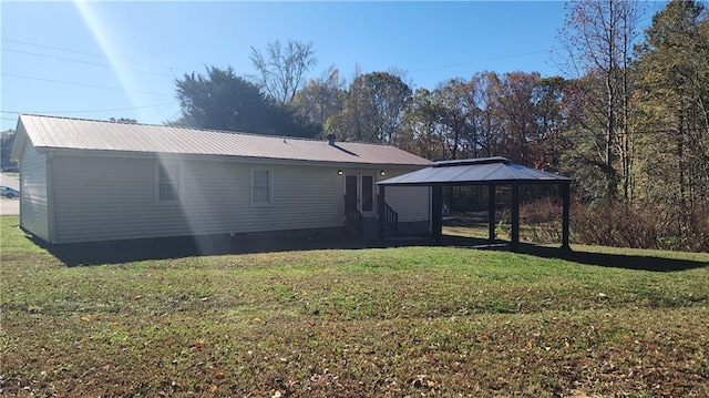 rear view of property featuring a gazebo and a lawn