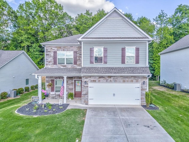 craftsman-style home with stone siding, a front yard, and a garage