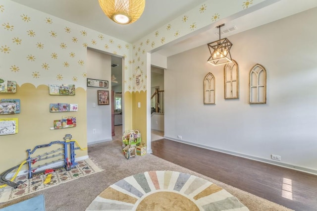 rec room featuring baseboards, wood finished floors, a chandelier, and wallpapered walls