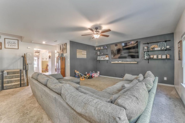 carpeted living area with ceiling fan, stairs, and baseboards