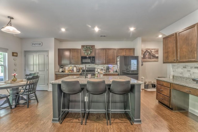 kitchen with black microwave, tasteful backsplash, range, stainless steel refrigerator with ice dispenser, and recessed lighting