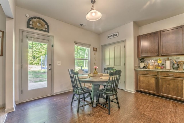 dining room with dark wood-type flooring, plenty of natural light, and baseboards