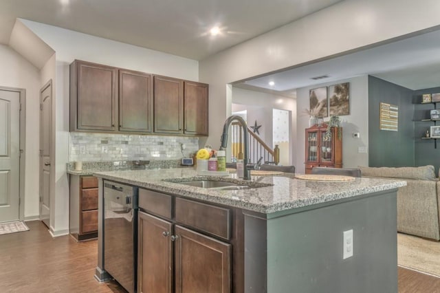 kitchen with stainless steel dishwasher, a sink, open floor plan, dark wood-style floors, and light stone counters