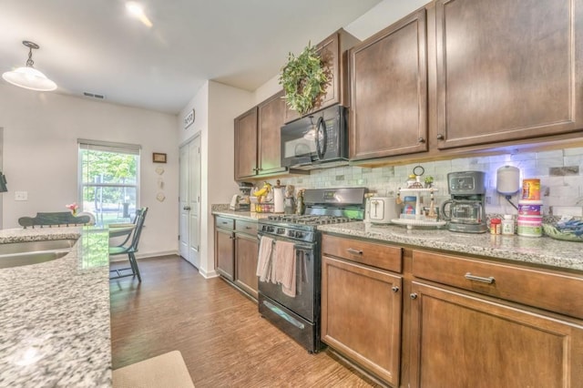 kitchen with black appliances, tasteful backsplash, wood finished floors, and light stone countertops