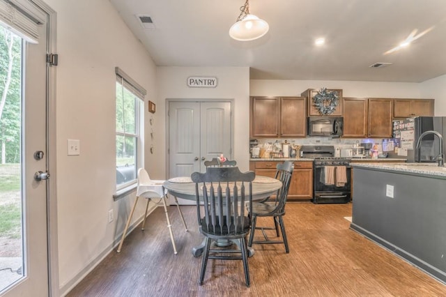 kitchen featuring black appliances, wood finished floors, decorative backsplash, and healthy amount of natural light