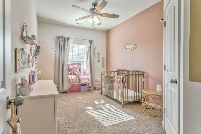 bedroom with light carpet, a crib, and ceiling fan