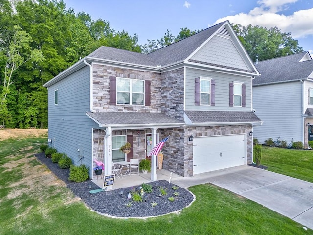 craftsman house with stone siding, a garage, a front lawn, and concrete driveway