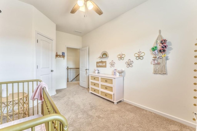 bedroom featuring light carpet, a crib, and baseboards