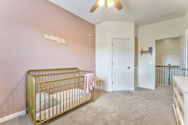 bedroom with carpet floors, baseboards, arched walkways, a nursery area, and a ceiling fan