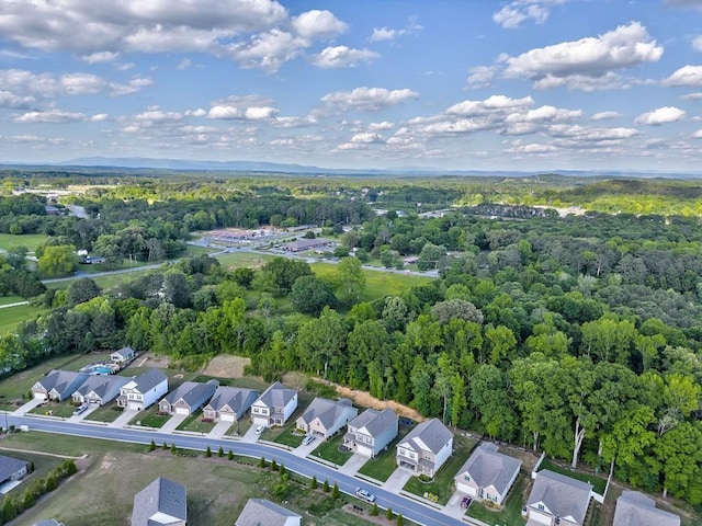 aerial view of property and surrounding area with a heavily wooded area and nearby suburban area