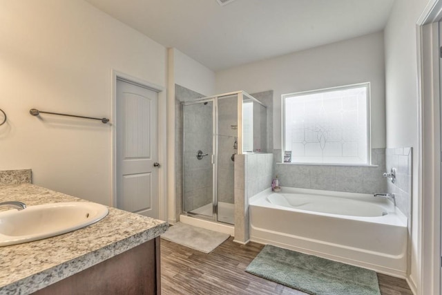 bathroom featuring a shower stall, wood finished floors, a bath, and vanity