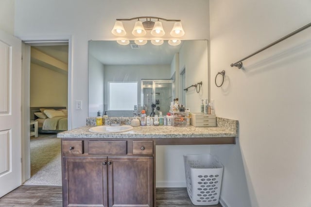 ensuite bathroom with wood finished floors, a shower stall, and vanity