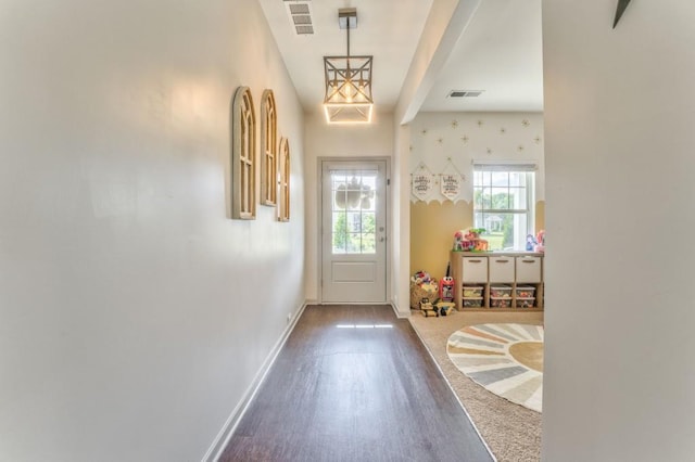 doorway featuring baseboards, dark wood-style floors, and beam ceiling