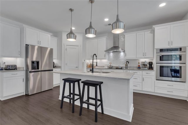 147 Wolf Creek Cv, Lagrange, GA 30240 - kitchen with appliances with stainless steel finishes, wall chimney range hood, white cabinetry, a kitchen bar, and recessed lighting