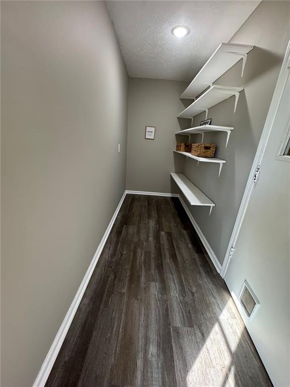 interior space with a textured ceiling and dark wood-type flooring