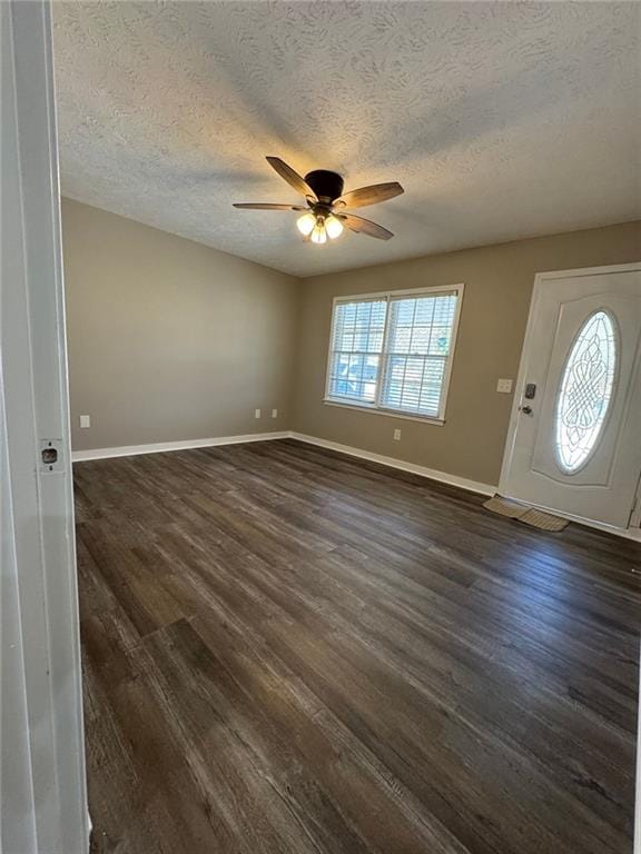 foyer entrance with ceiling fan, dark wood-type flooring, and a textured ceiling