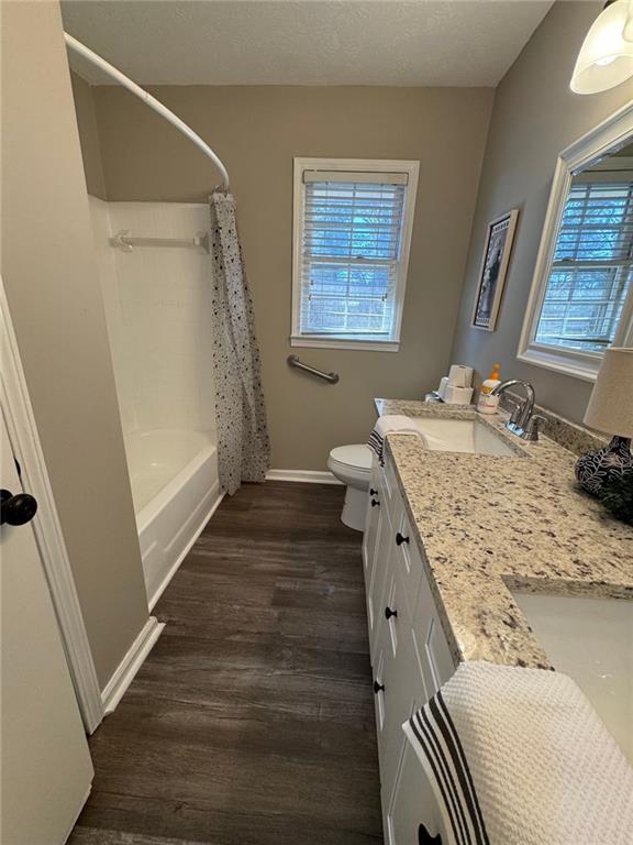 full bathroom featuring hardwood / wood-style floors, vanity, toilet, and shower / bath combo