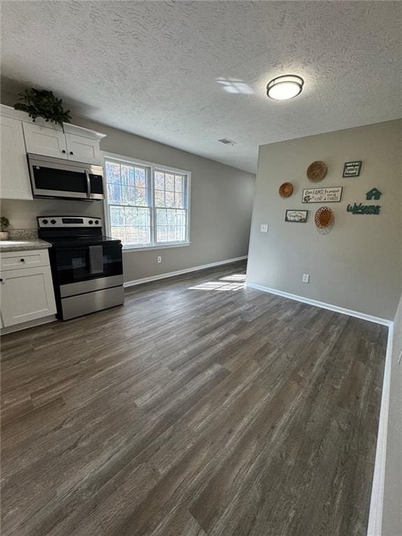 kitchen featuring dark wood-type flooring, white cabinets, stainless steel appliances, and a textured ceiling