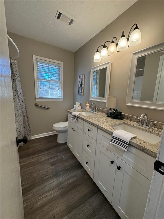 bathroom with hardwood / wood-style floors, vanity, toilet, and a textured ceiling