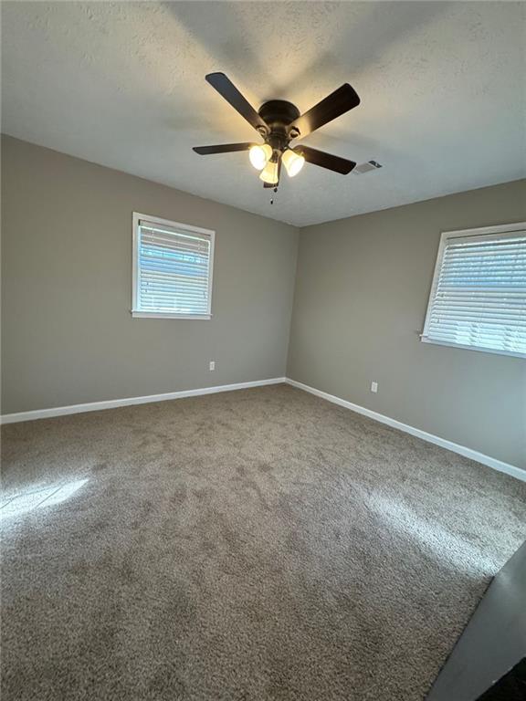 carpeted empty room featuring a textured ceiling and ceiling fan