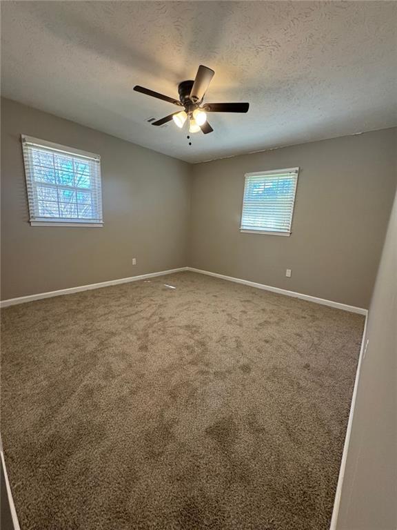 empty room featuring carpet flooring, ceiling fan, and a textured ceiling