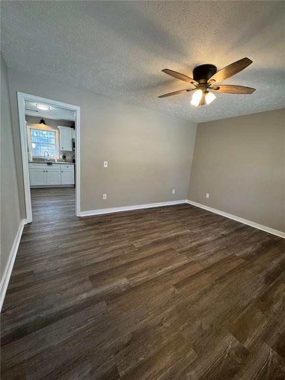 unfurnished room with ceiling fan, sink, dark wood-type flooring, and a textured ceiling