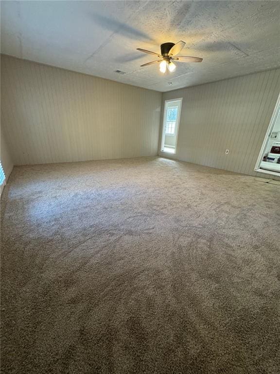 unfurnished room with ceiling fan, carpet floors, and a textured ceiling